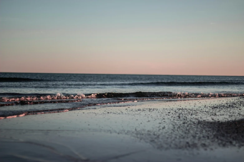 a wave rolls into the shore with sand