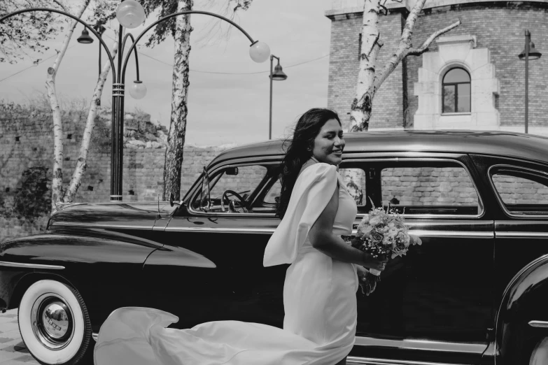 the bride poses beside a classic car in black and white