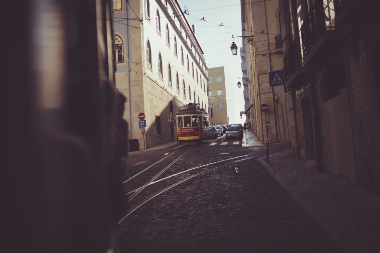 a yellow and red tram coming down a street next to tall buildings