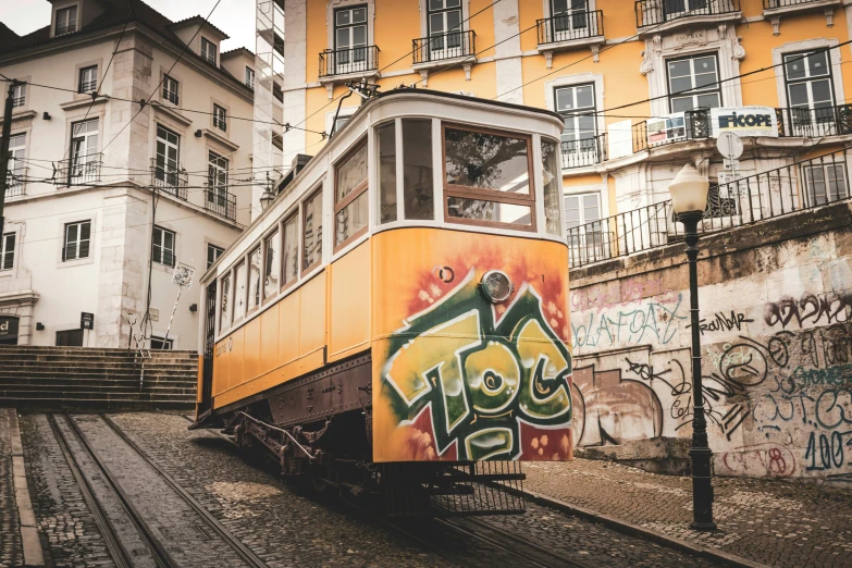 a yellow and orange train with graffiti on it