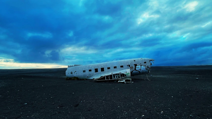 a propeller plane is parked on the ground under a cloudy sky