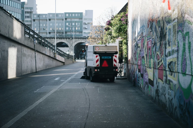 a truck drives down an alley near graffiti