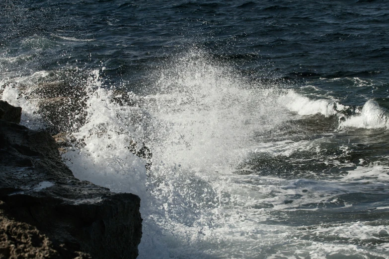 a large wave splashing over the edge of a rock