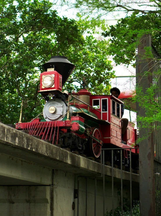 a train on a track near trees and a bridge