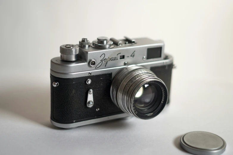 old style camera laying on the floor beside a coin