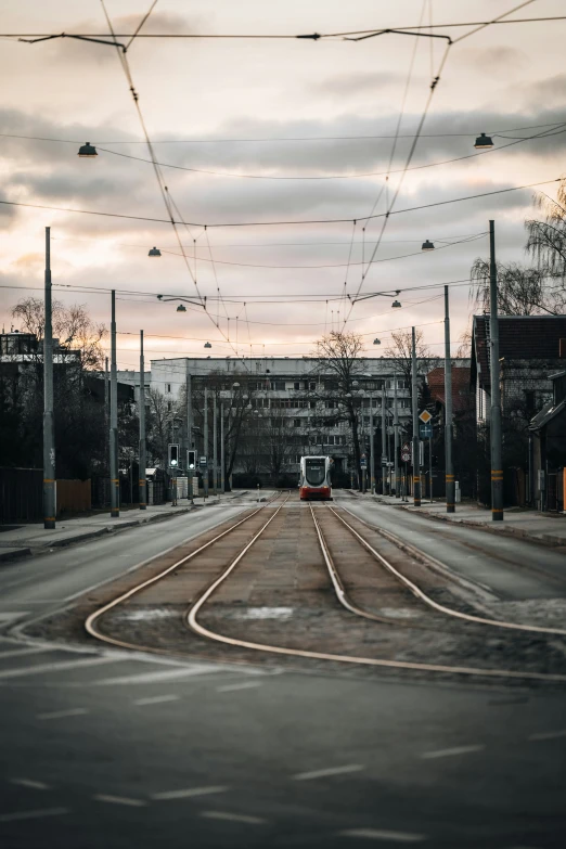 empty street with cars passing on one side and cloudy sky