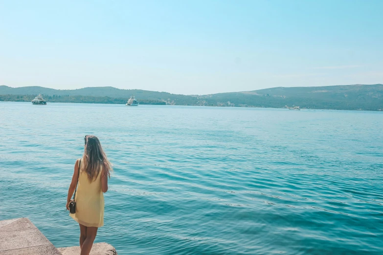 a girl is looking out to sea from the shore