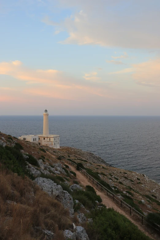 an empty lighthouse sits on a rocky coastline