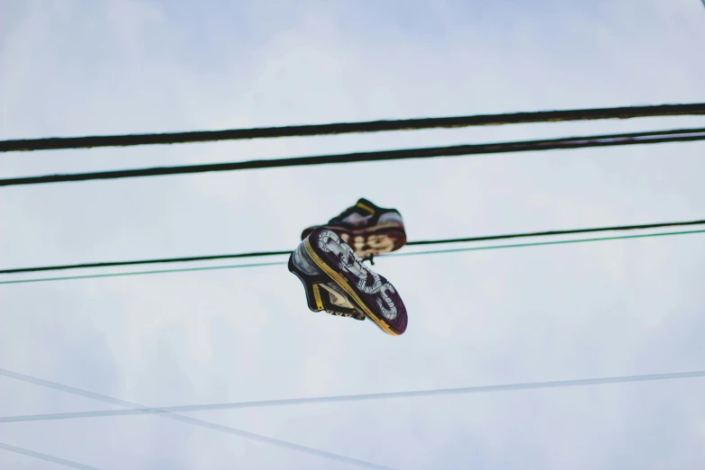 shoes are on electrical wire above against the sky