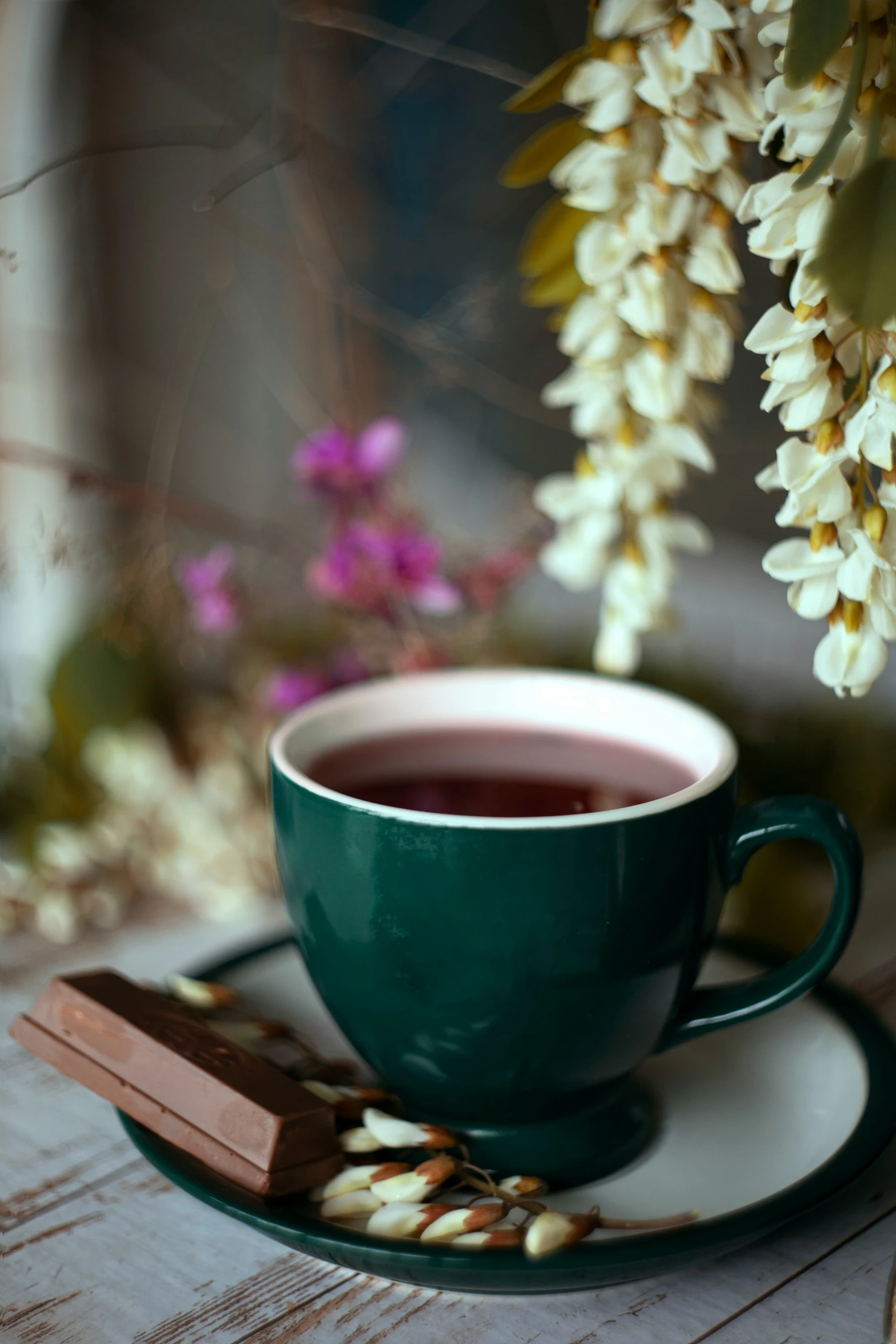 a cup and saucer that are next to a piece of chocolate