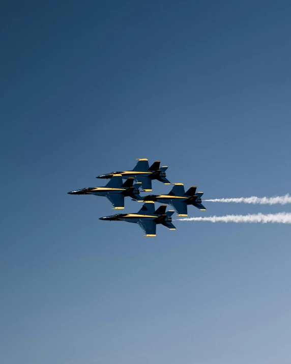 four fighter jets flying through the sky leaving smoke trails behind them