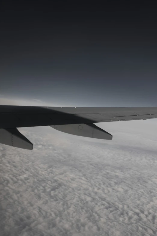 an airplane wing flying in the air over clouds