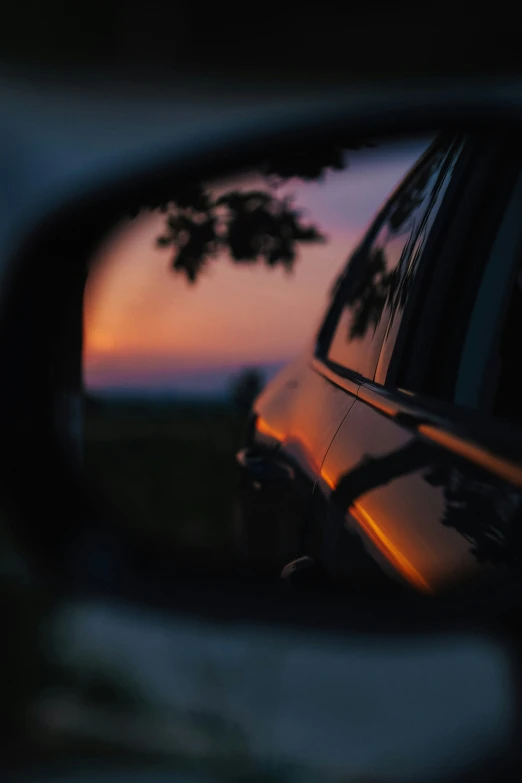 sunset in the rear view mirror of a vehicle