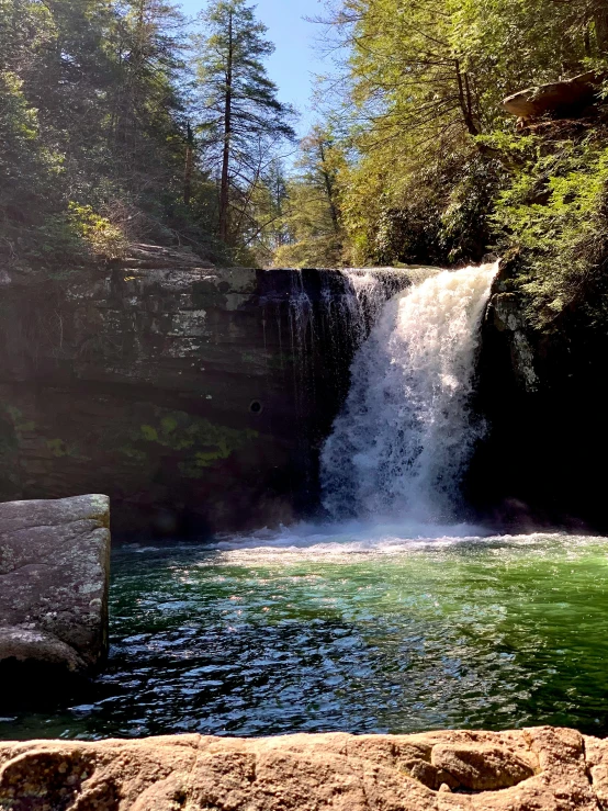 a waterfall is flowing into the green water