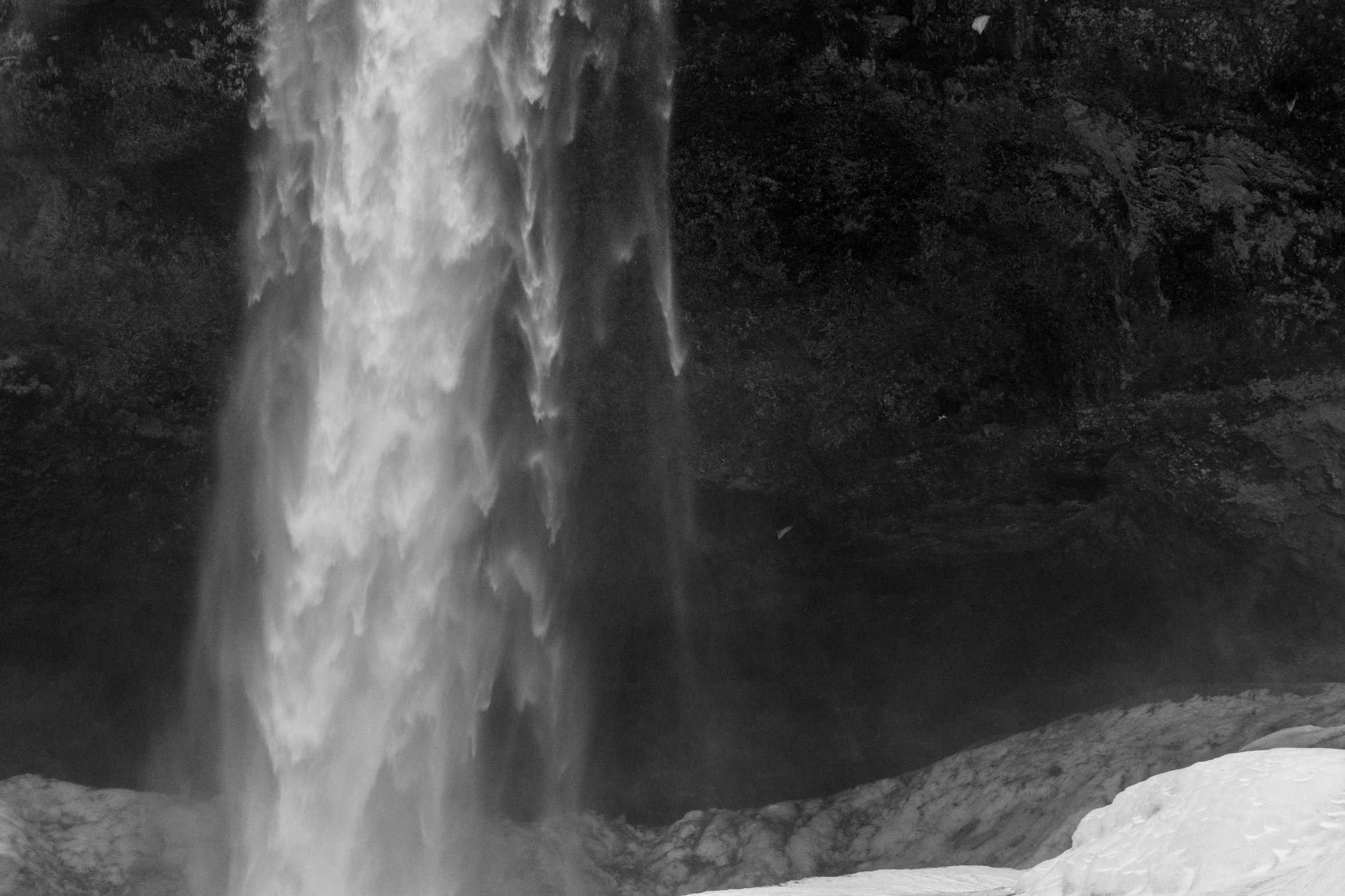 an old po of a large waterfall with a man sitting near the base