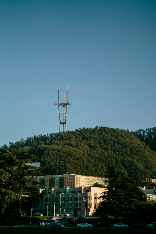 a radio tower stands on top of a green hill