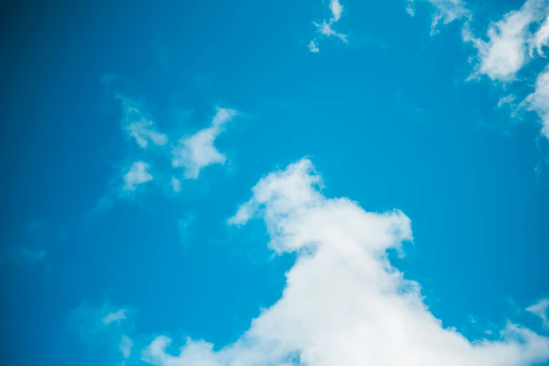 an airplane flying through the blue sky near clouds