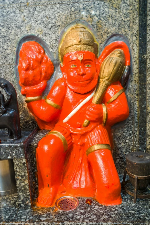 a orange statue sitting on top of a sidewalk next to a wall