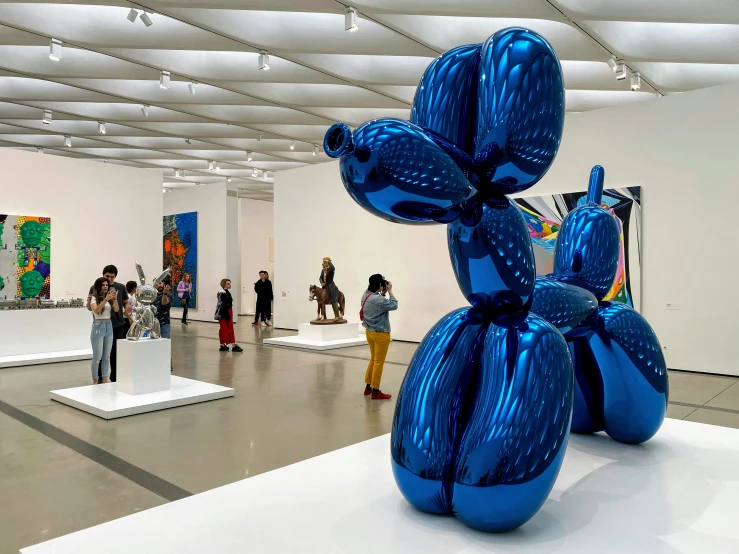 people standing inside of an art gallery with large balloons