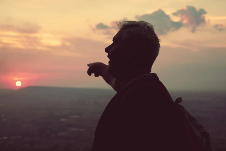 a man is looking down at the sunset