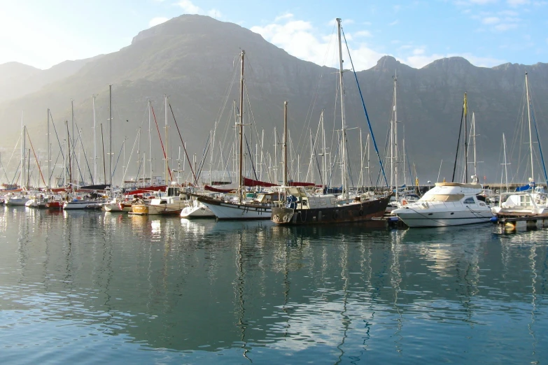 a harbor filled with small sailboats near mountains