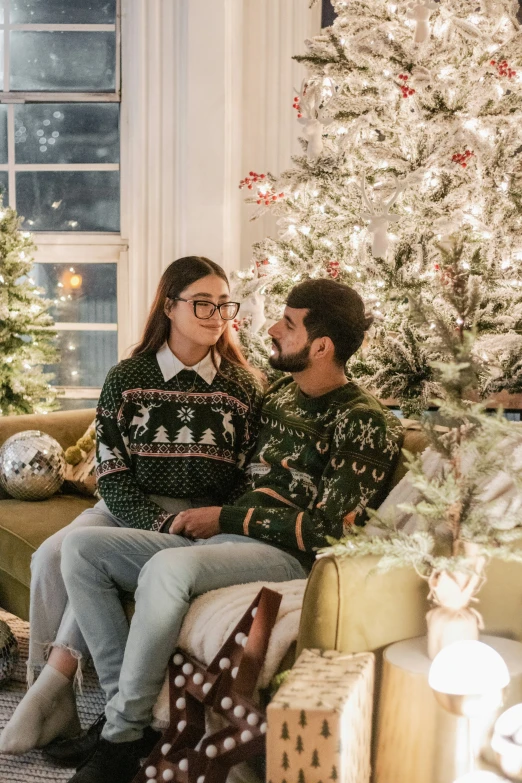 a young couple dressed up and posing for a po next to the christmas tree