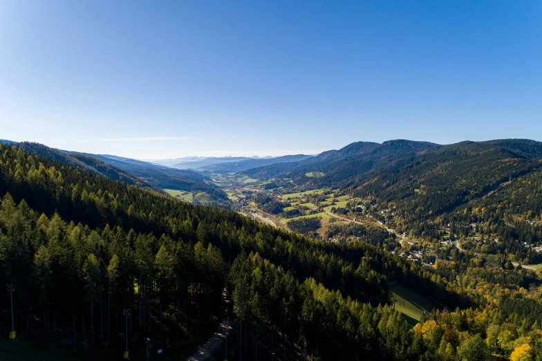 a view of a valley with many trees in the foreground and a town on the far side