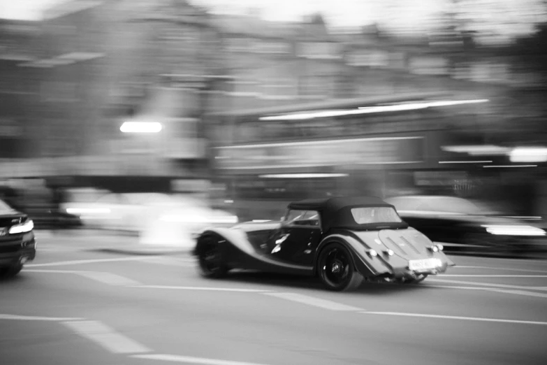 two cars on a street, going faster