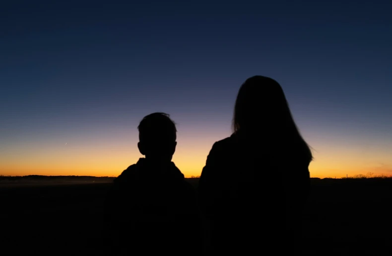 two people are in the dark watching the sunset