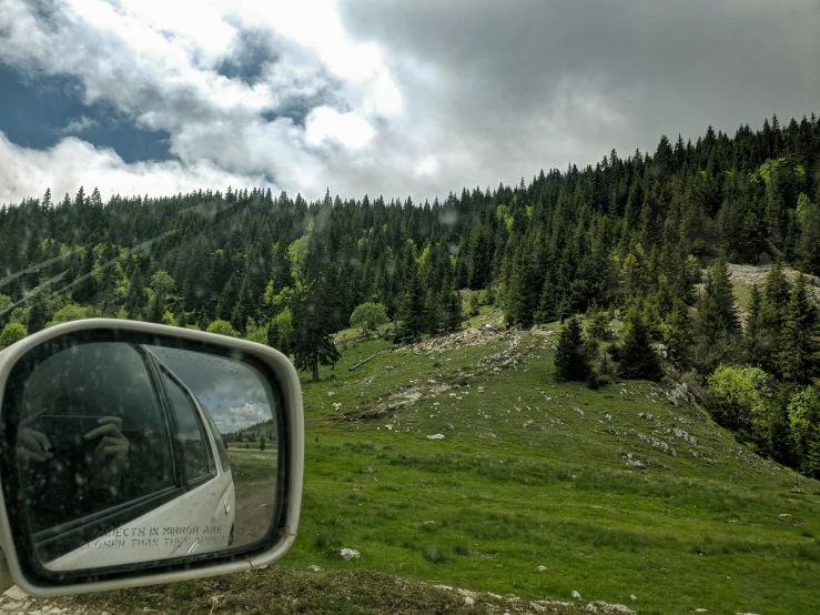 the landscape is seen through an angled side mirror of a vehicle