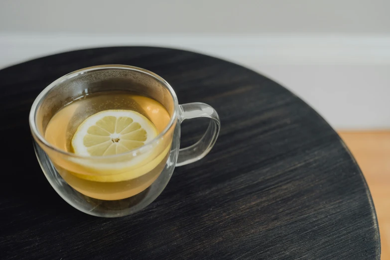 a glass mug with lemon sitting on top of a table