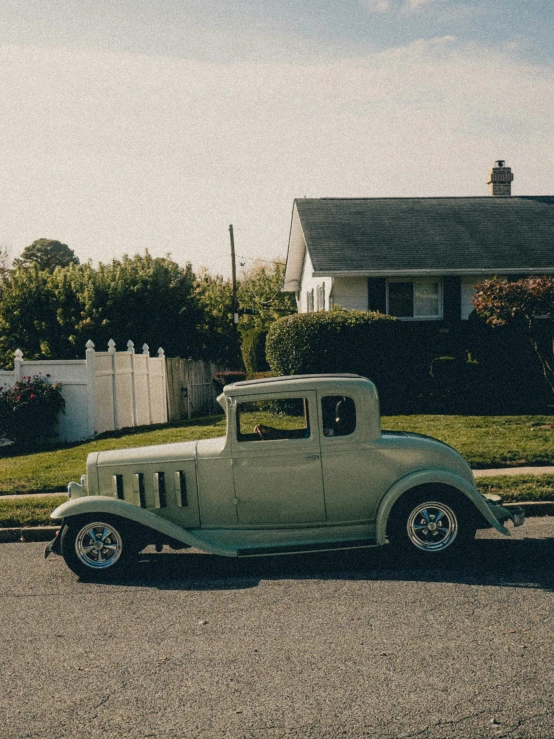a green old truck parked in front of a house