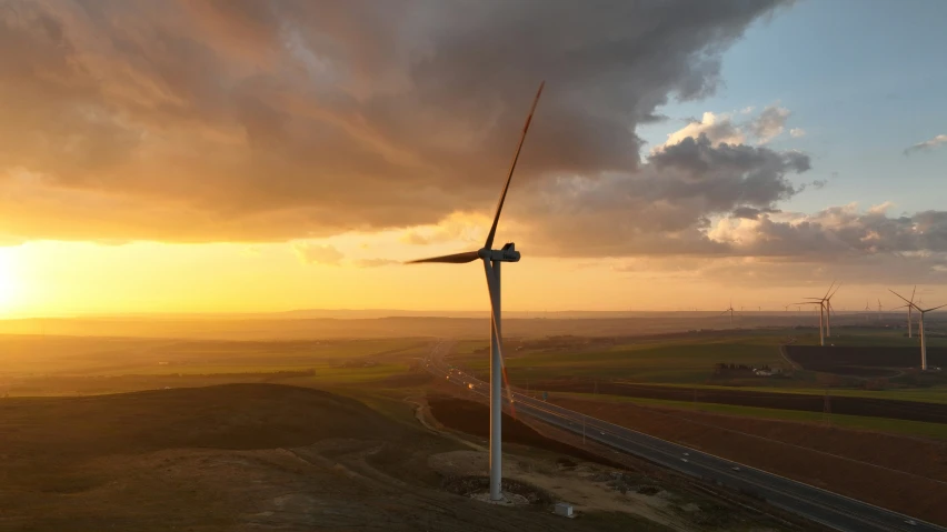 a view of some windmills at sunset over a highway