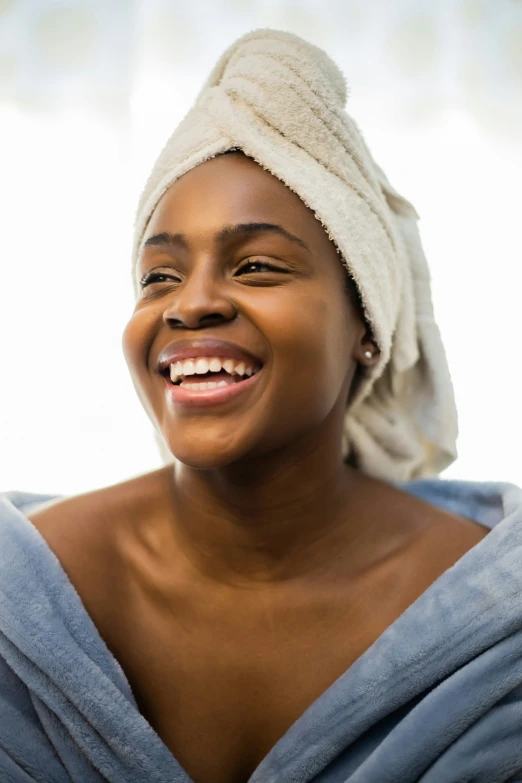 a women who is smiling and wearing a towel on her head