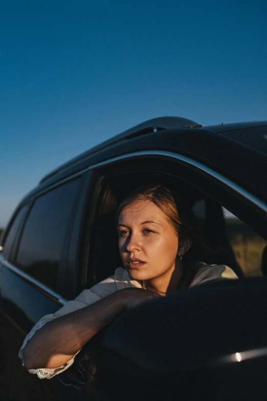 a woman sitting in her car looking out the window