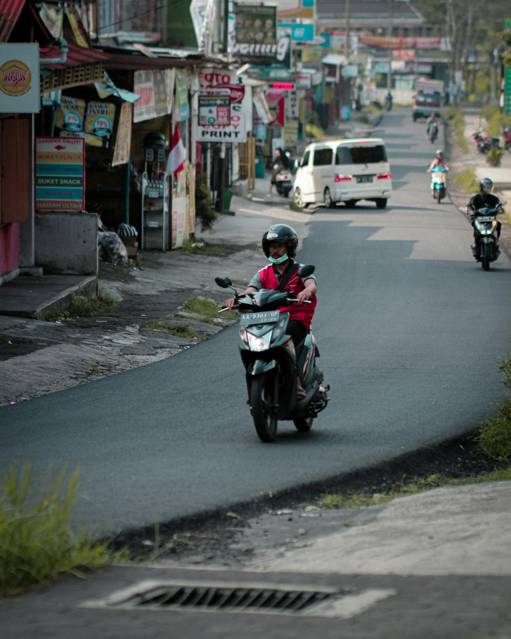 two motorcycles driving down the road in the distance with shops on each side