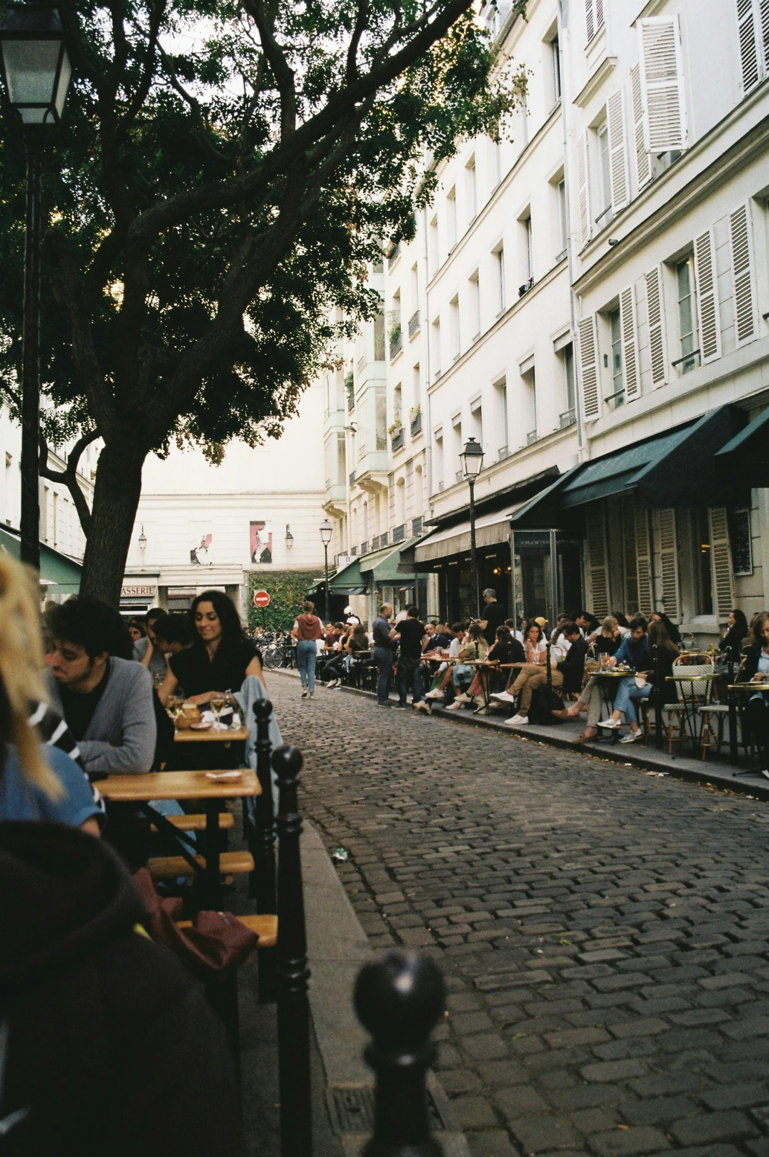 people are sitting in outdoor dining spaces on a city street