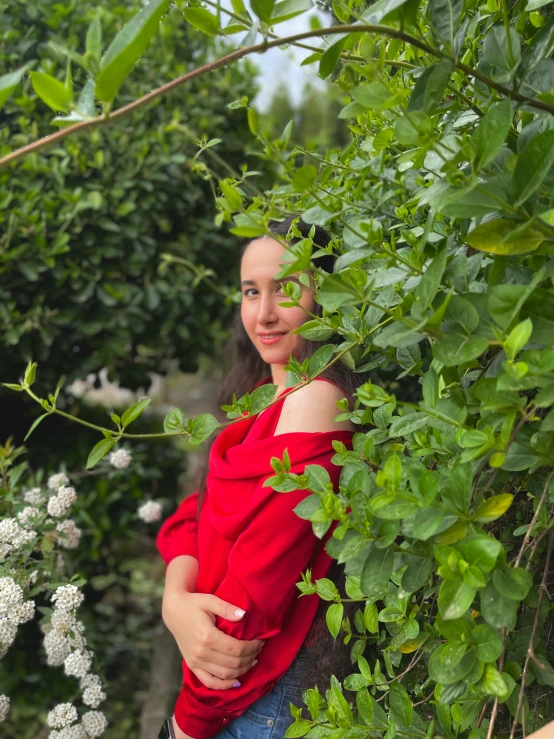 woman in red top and blue jeans standing between plants