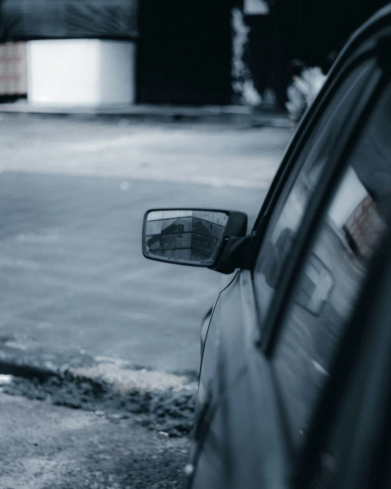 this car is stopped in the street and the side mirror has the reflection of a person