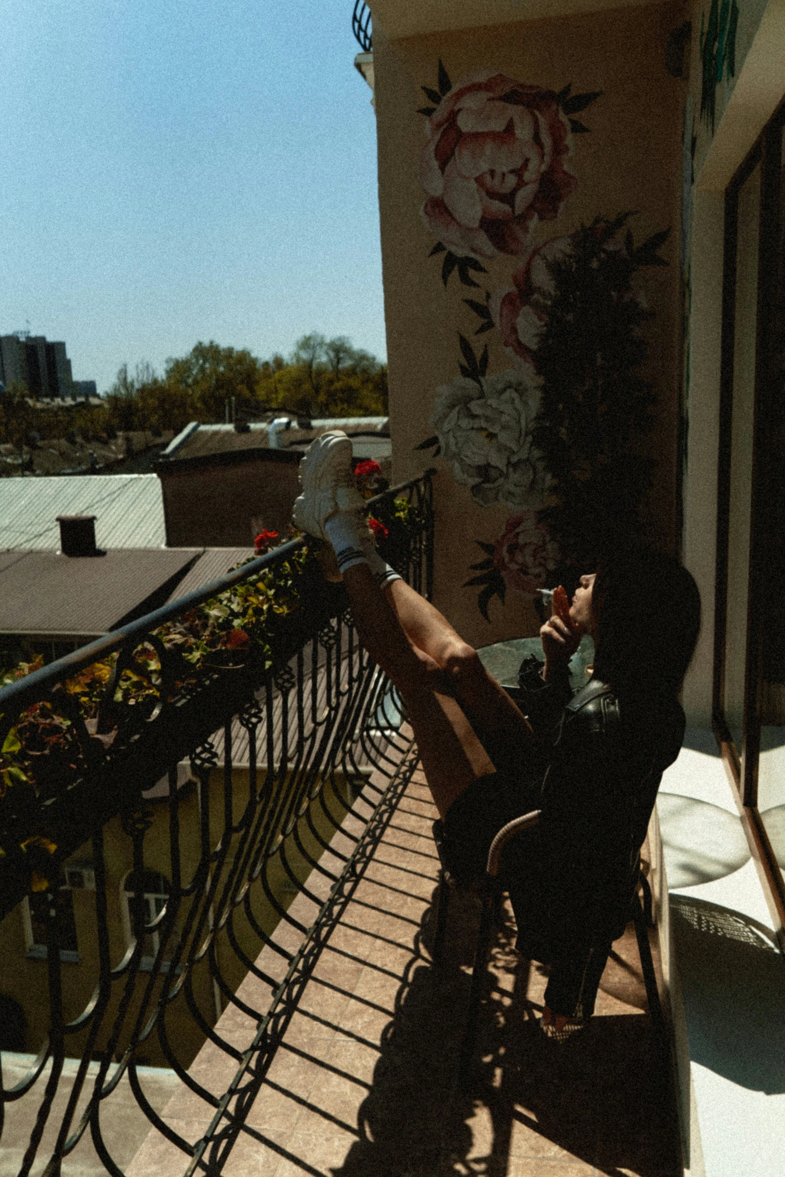 a woman sitting on top of a balcony next to a wall