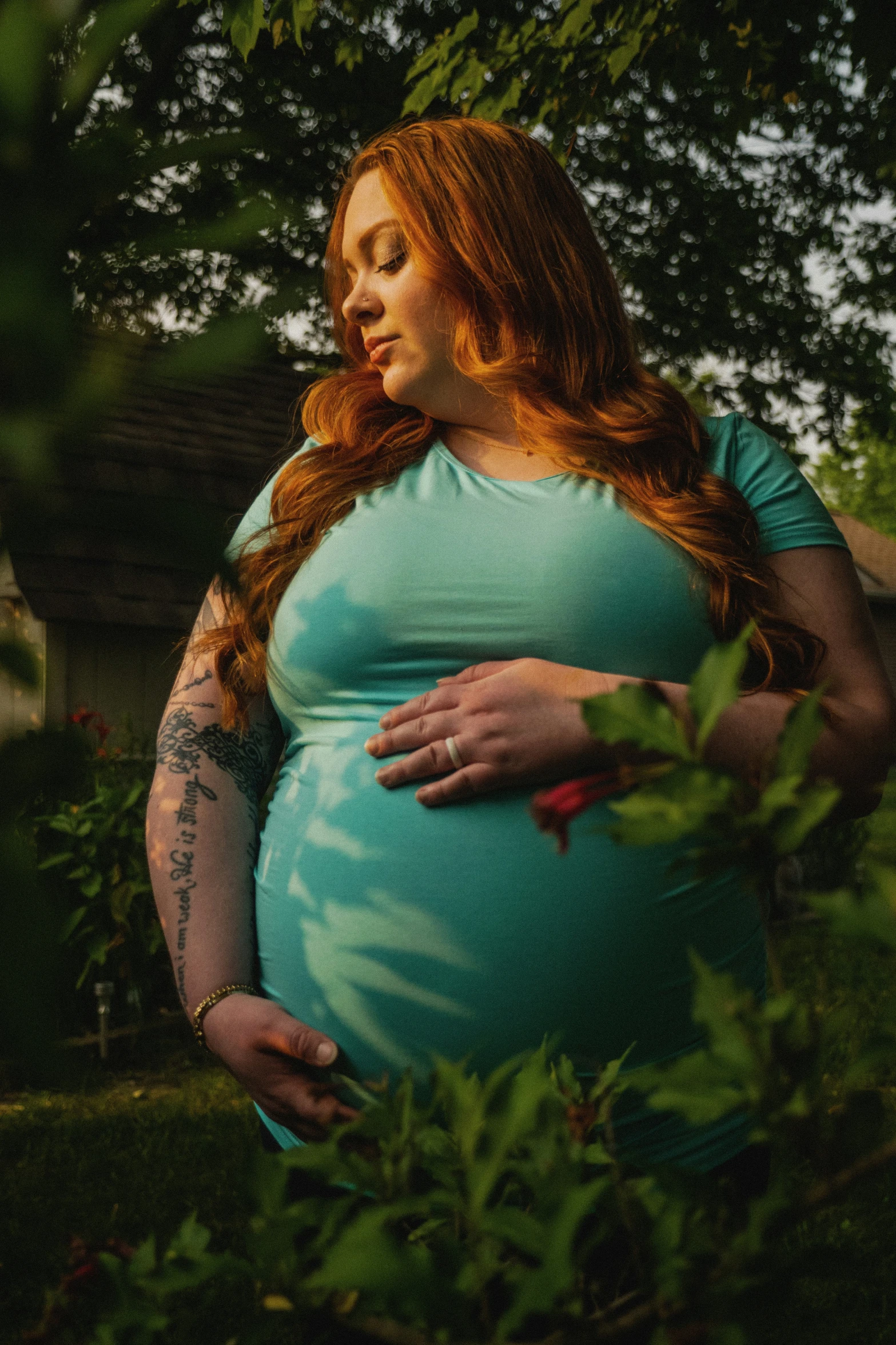 a pregnant woman standing in a field holding her stomach