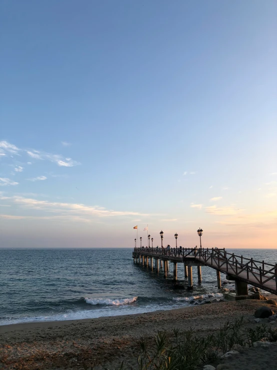 a long pier on the beach next to the ocean