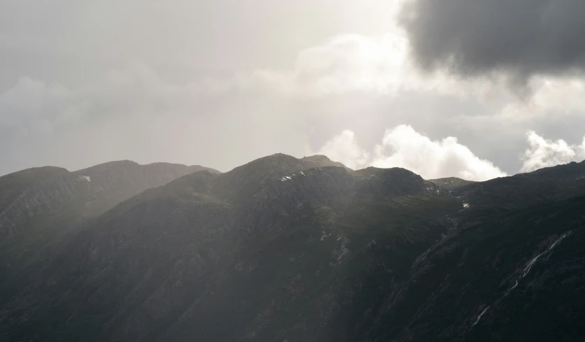 the silhouette of a mountain peak is shown as clouds loom overhead