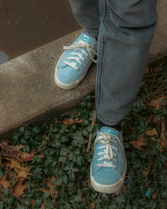 a person with sneakers on standing near a street curb