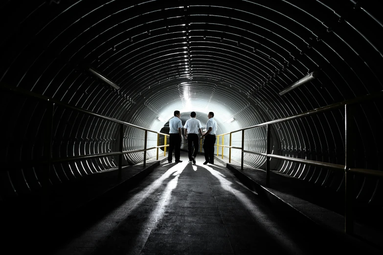 three people walking through a tunnel made of circles