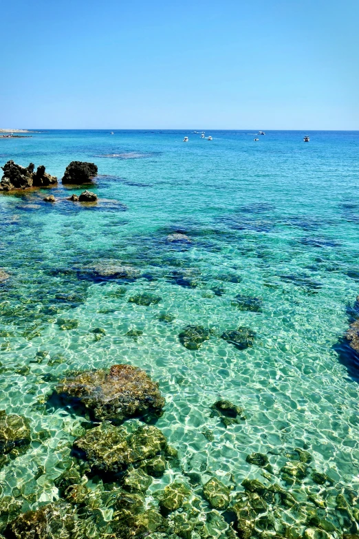 several rocks in clear water in front of blue skies