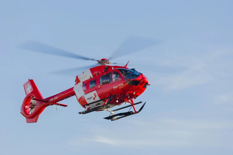 a red and white helicopter in the air on a clear day