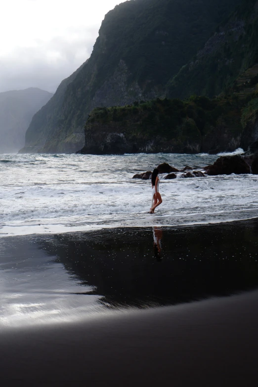 a person on a beach walking through the water