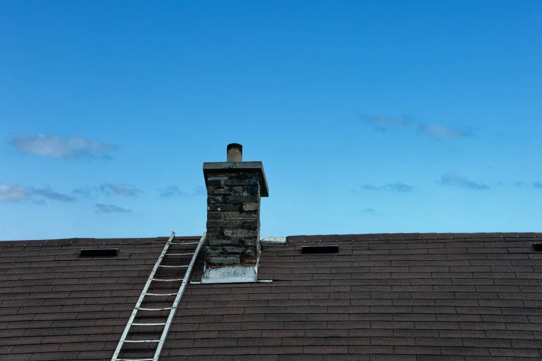 a chimney on top of a tiled roof with a ladder