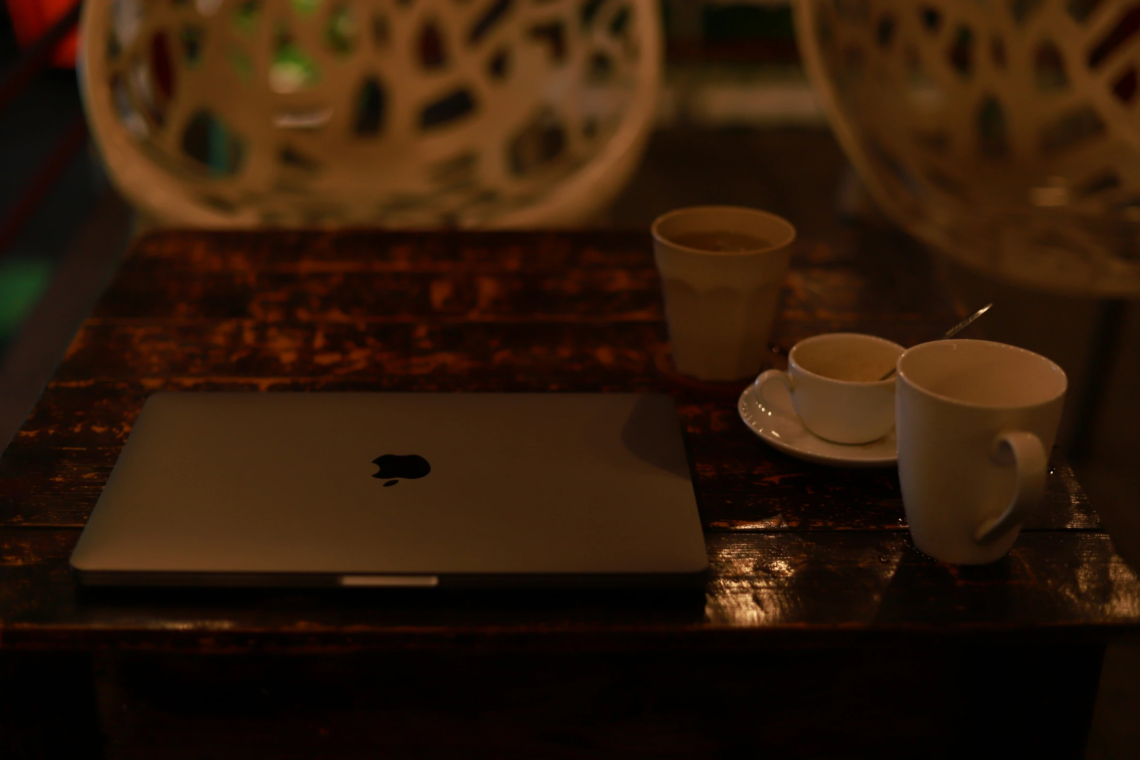 a laptop and cups on a table with lights